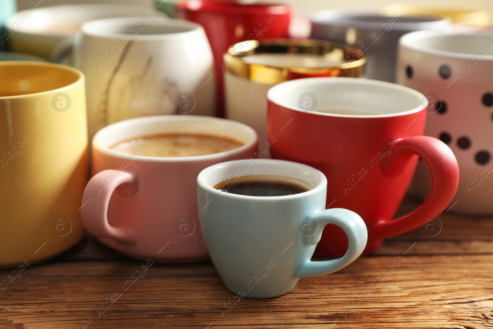 Photo of Many cups of different coffees on wooden table