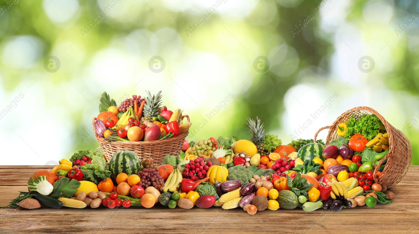 Image of Assortment of fresh organic vegetables and fruits on wooden table against blurred green background. Banner design 