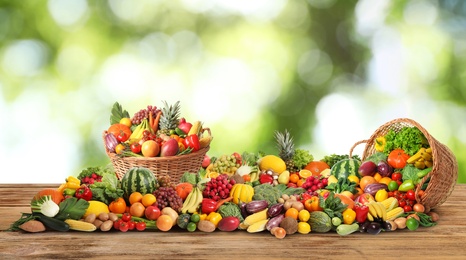 Assortment of fresh organic vegetables and fruits on wooden table against blurred green background. Banner design 