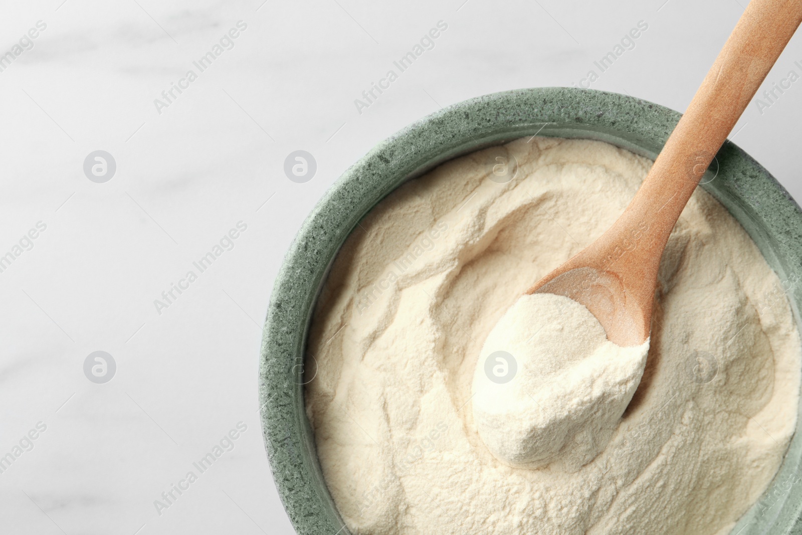 Photo of Bowl and spoon of agar-agar powder on white marble table, top view