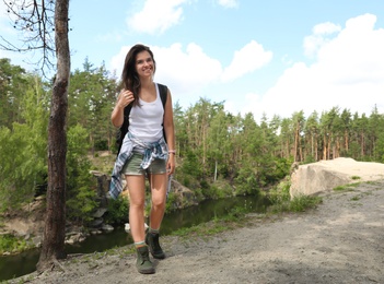 Young woman with backpack in wilderness. Camping season