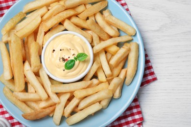 Photo of Delicious French fries and cheese sauce on white wooden table