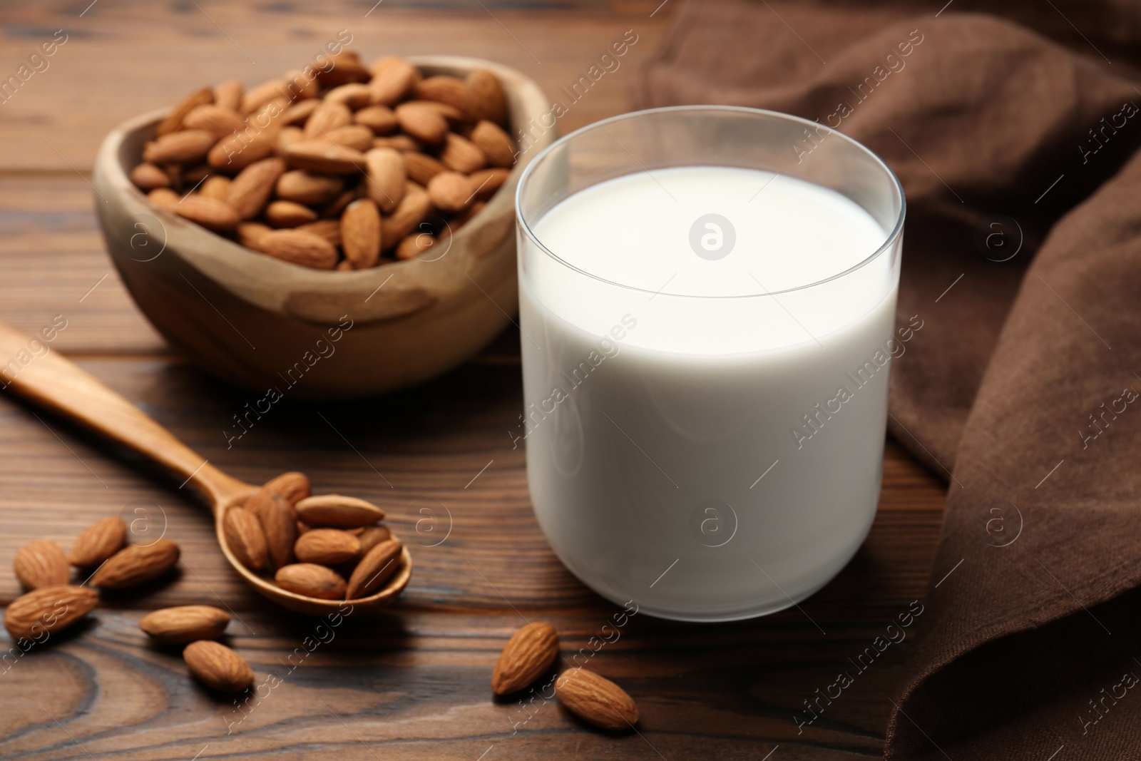 Photo of Glass of almond milk and almonds on wooden table