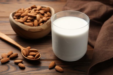 Glass of almond milk and almonds on wooden table