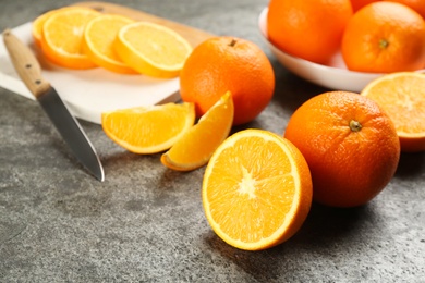 Photo of Whole and cut delicious ripe oranges on grey table