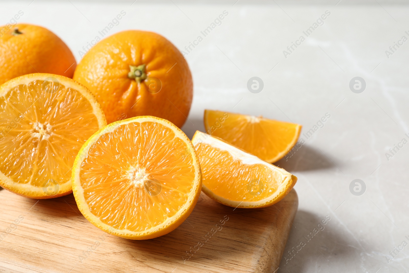 Photo of Wooden board with ripe oranges on table. Space for text