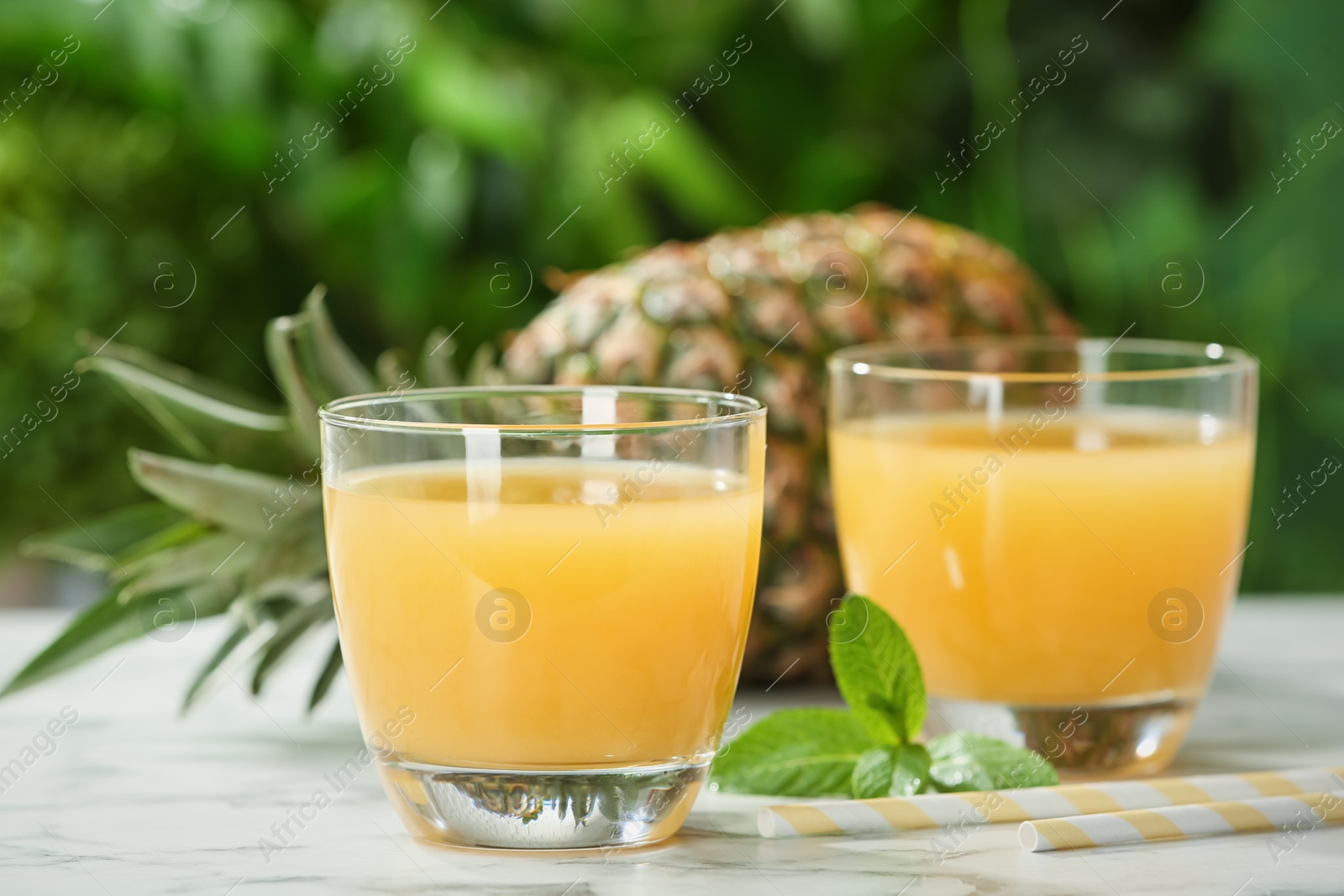 Photo of Composition with delicious pineapple juice on table against blurred background