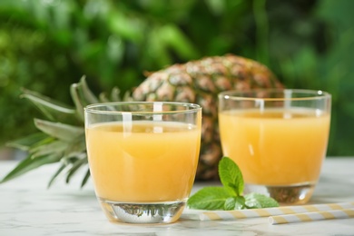 Photo of Composition with delicious pineapple juice on table against blurred background