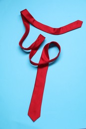 Photo of Red necktie on light blue background, top view