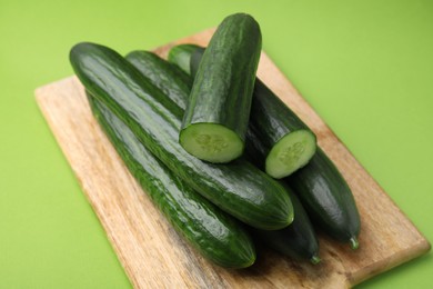 Many fresh cucumbers on green background, closeup