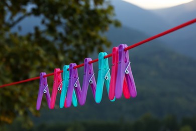 Photo of Colorful clothespins hanging on washing line outdoors