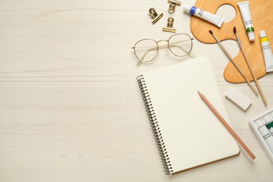 Photo of Flat lay composition with blank sketchbook on white wooden table. Space for text