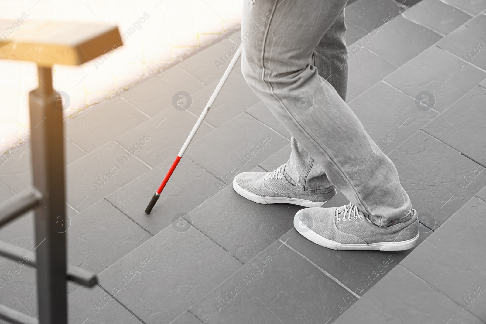 Photo of Blind person with cane going down stairs outdoors, closeup