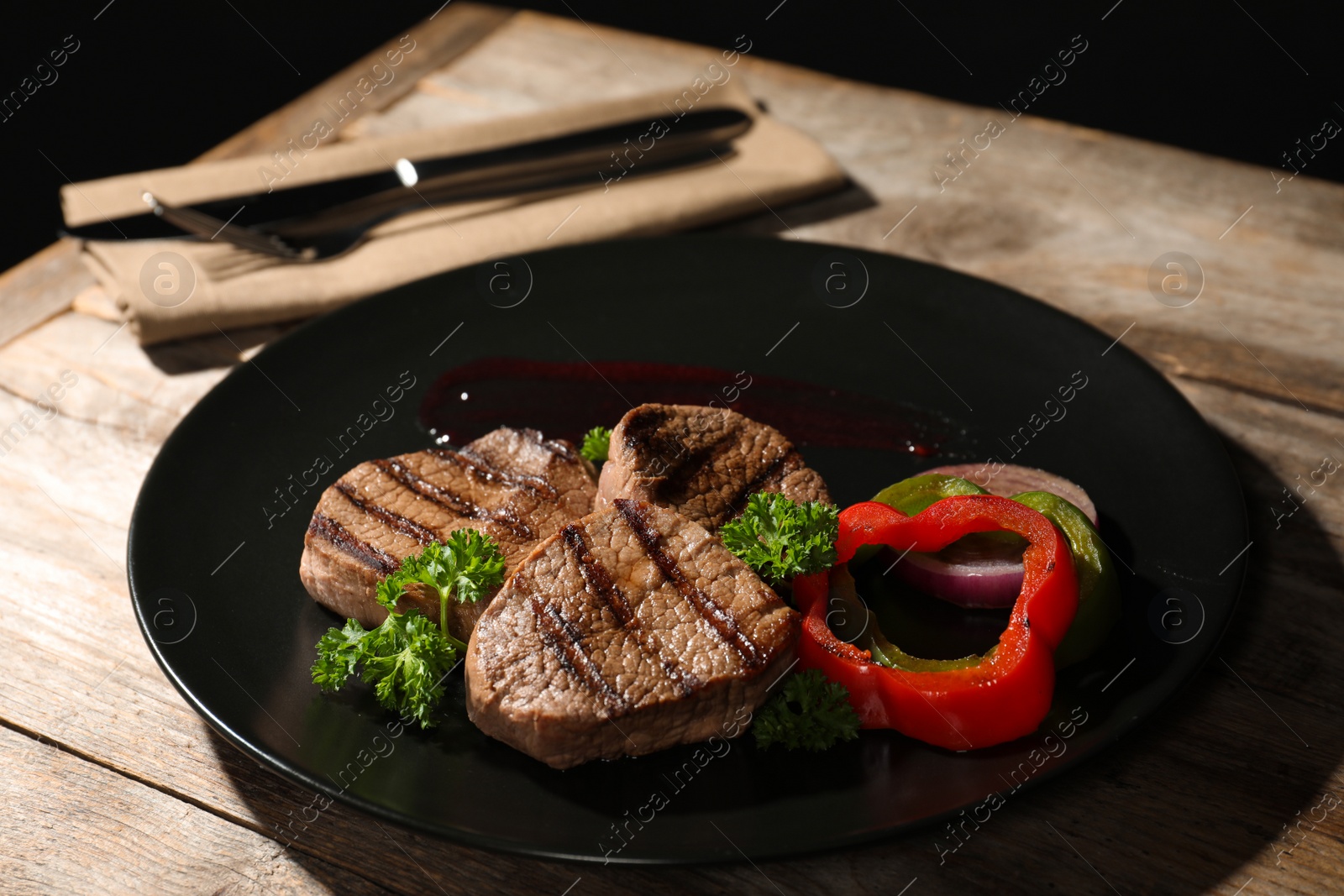 Photo of Plate with grilled meat and garnish on table