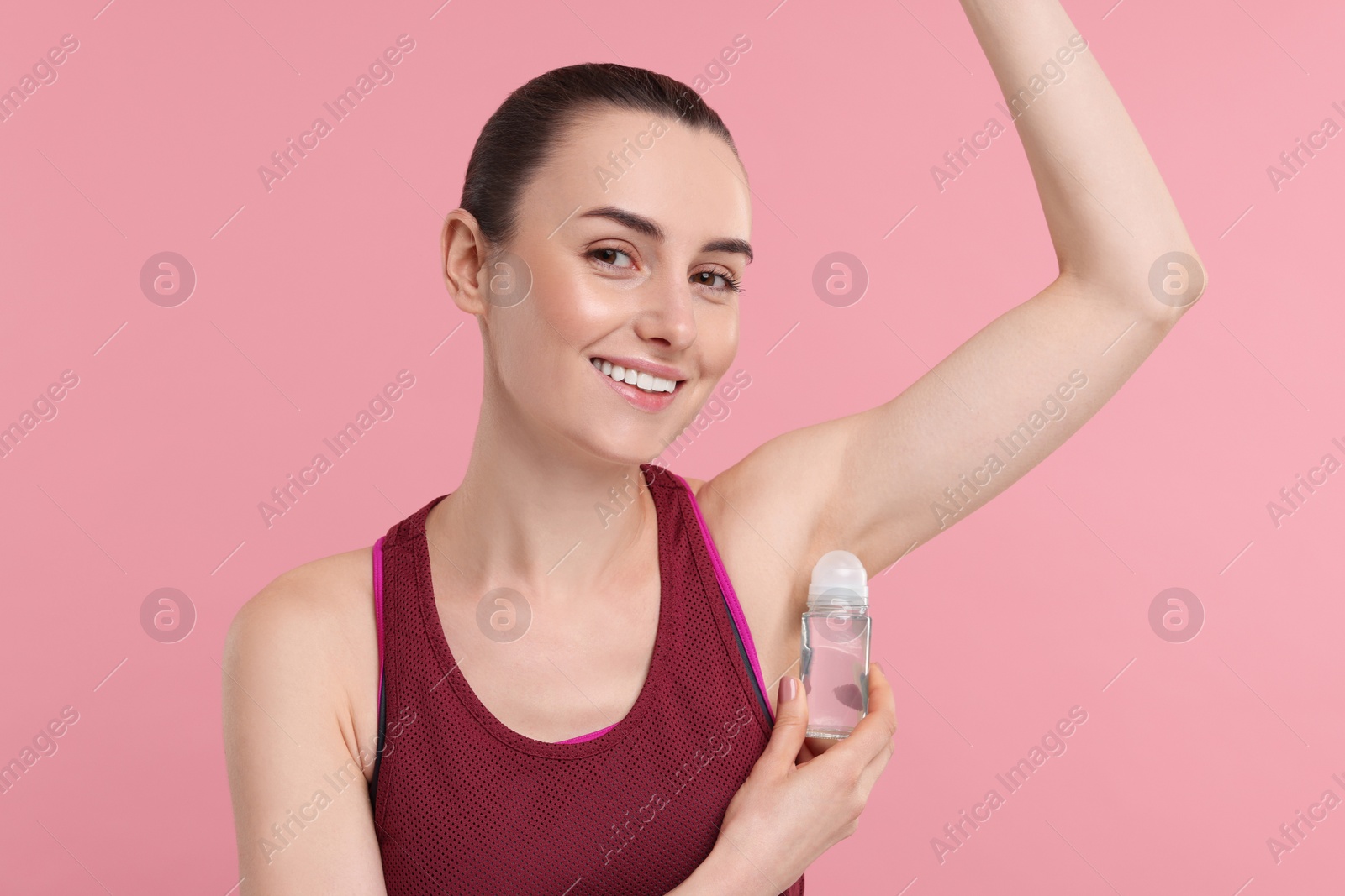 Photo of Beautiful woman applying deodorant on pink background