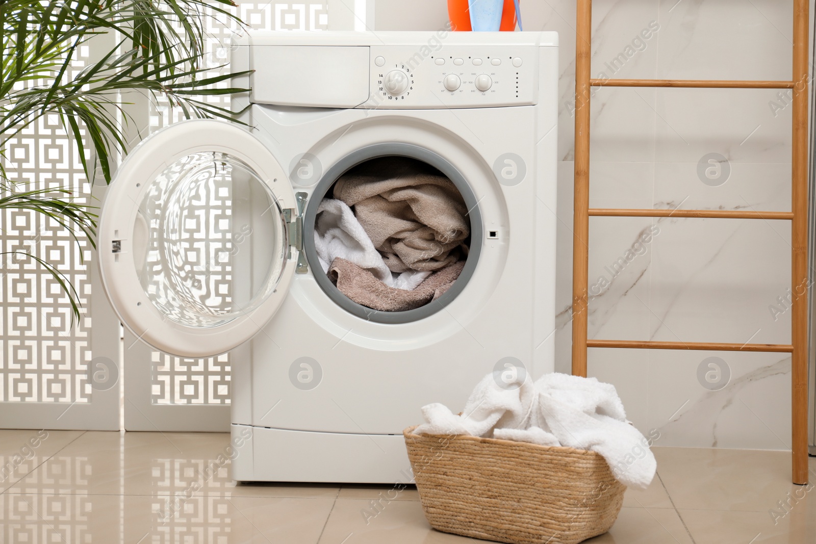 Photo of Modern washing machine with towels in bathroom