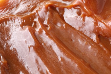 Photo of Tasty sweet caramel sauce as background, closeup