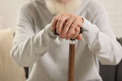 Photo of Senior man with walking cane indoors, closeup