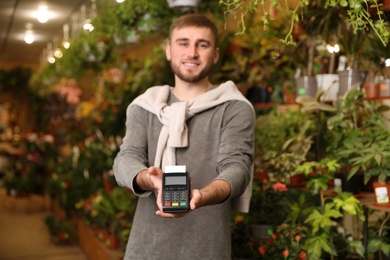 Smiling seller holding payment terminal in floral shop