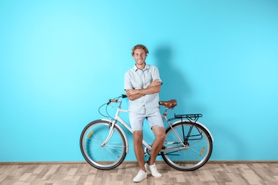 Photo of Handsome man with bicycle against color wall