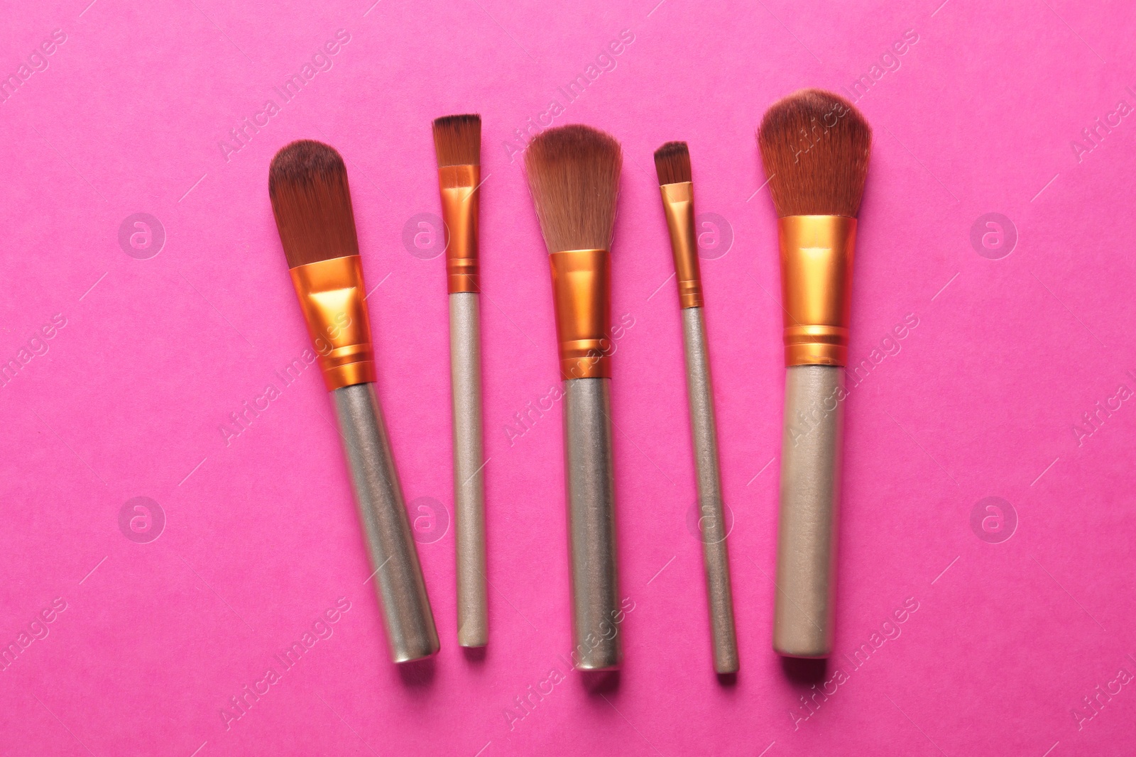 Photo of Different makeup brushes on pink background, flat lay