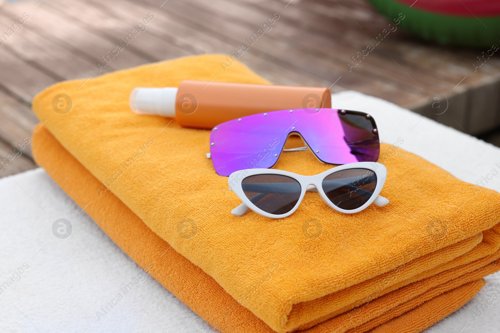 Photo of Beach towels, sunglasses and sunscreen on sunbed at resort, closeup