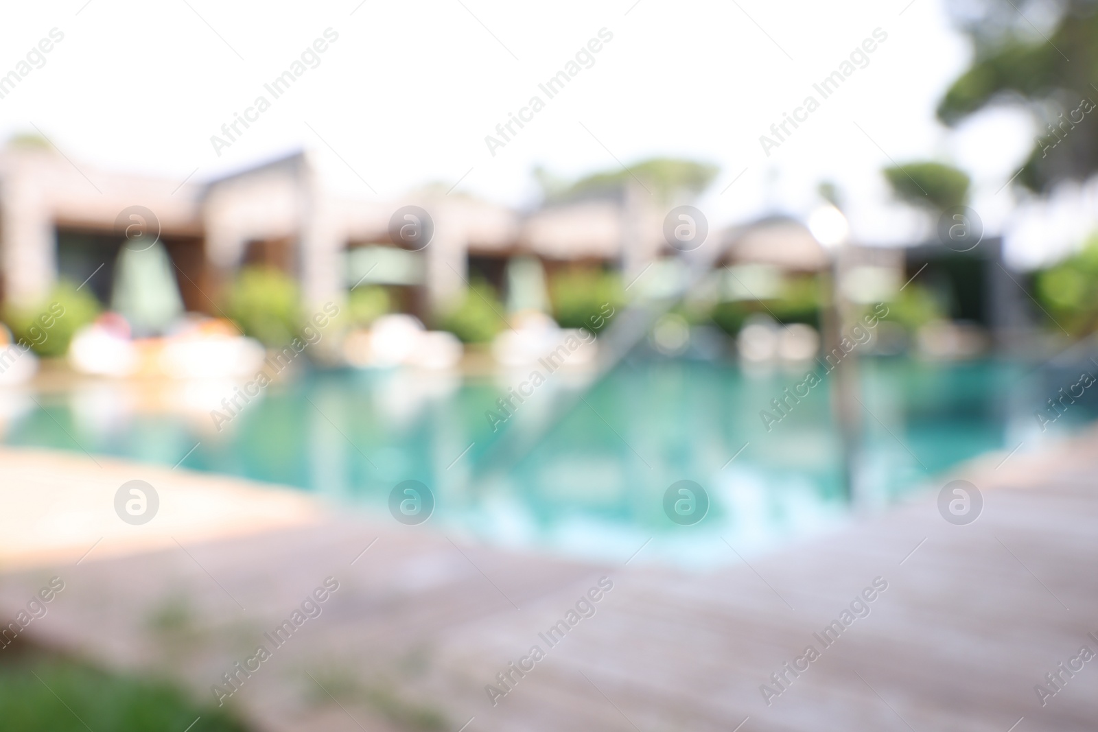 Photo of Outdoor swimming pool with wooden deck, blurred view. Luxury resort