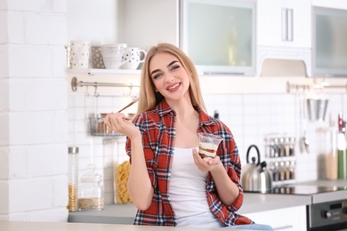 Young woman with yogurt in kitchen