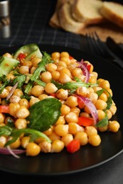 Photo of Delicious fresh chickpea salad on black table, closeup