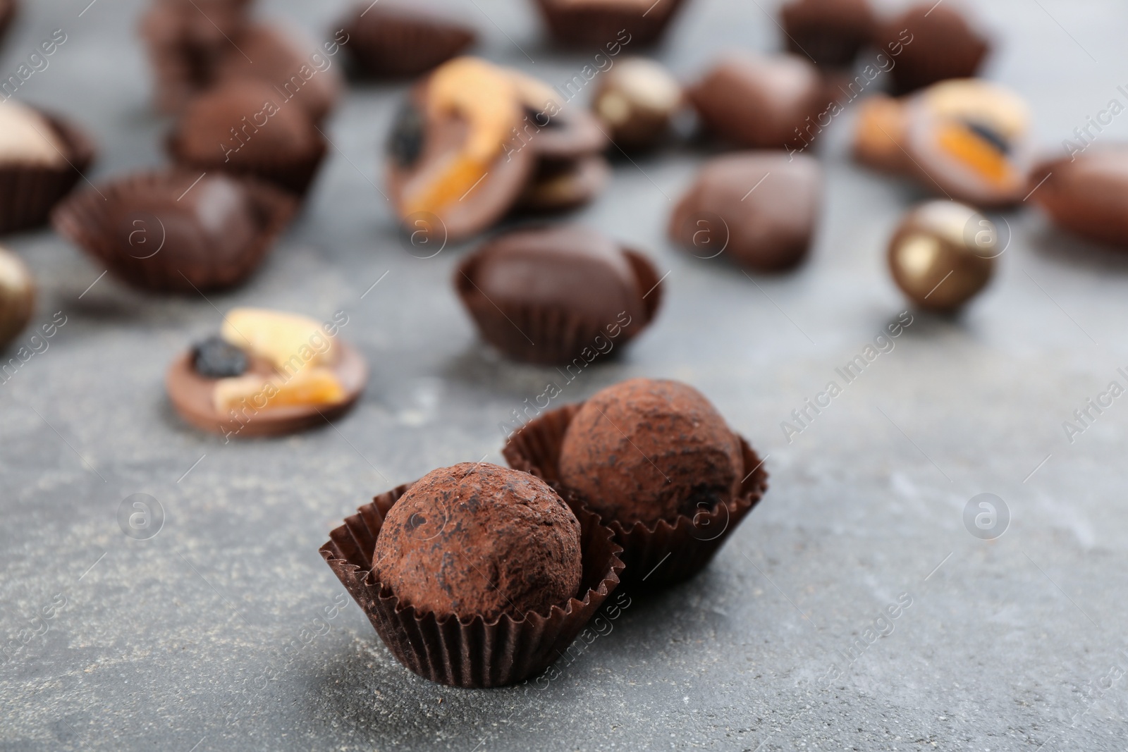 Photo of Different delicious chocolate candies on grey table, closeup