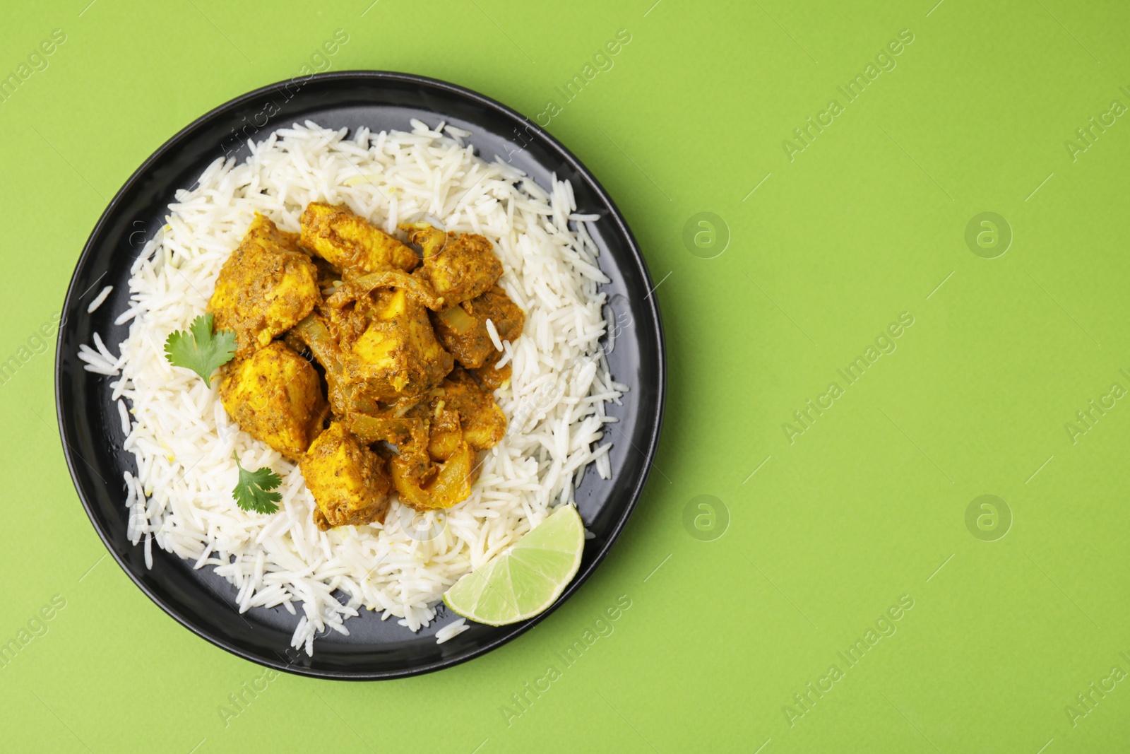 Photo of Delicious chicken curry with rice on green background, top view. Space for text