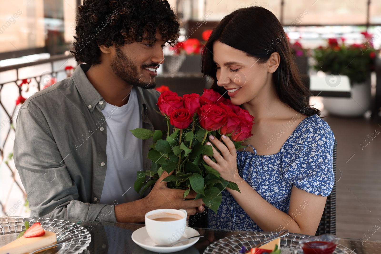 Photo of International dating. Handsome man presenting roses to his girlfriend in restaurant