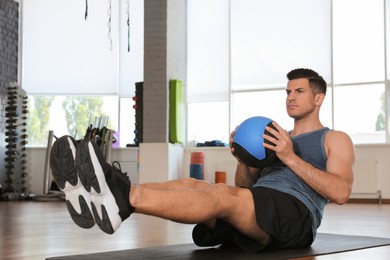 Photo of Athletic man exercising with medicine ball in modern gym