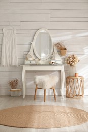 Wooden dressing table with decorative elements and makeup products in room. Interior design