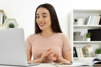 Home workplace. Happy woman working on laptop at white desk in room