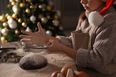 Photo of Little child making Christmas cookies at table indoors, closeup