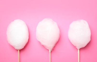 Photo of Sticks with yummy cotton candy on color background, top view