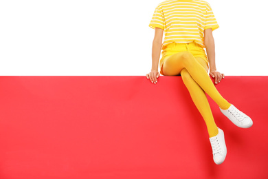 Woman wearing yellow tights sitting on color background, closeup. Space for text