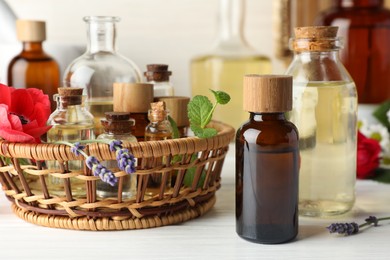 Photo of Aromatherapy. Different essential oils and flowers on white wooden table