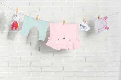 Photo of Baby clothes hanging on washing line near white brick wall