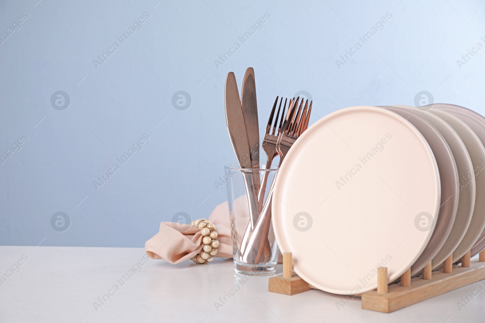 Photo of Set of clean tableware on light table. Space for text