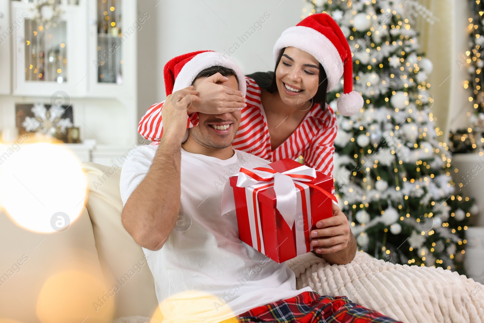 Photo of Young woman presenting Christmas gift to her boyfriend at home