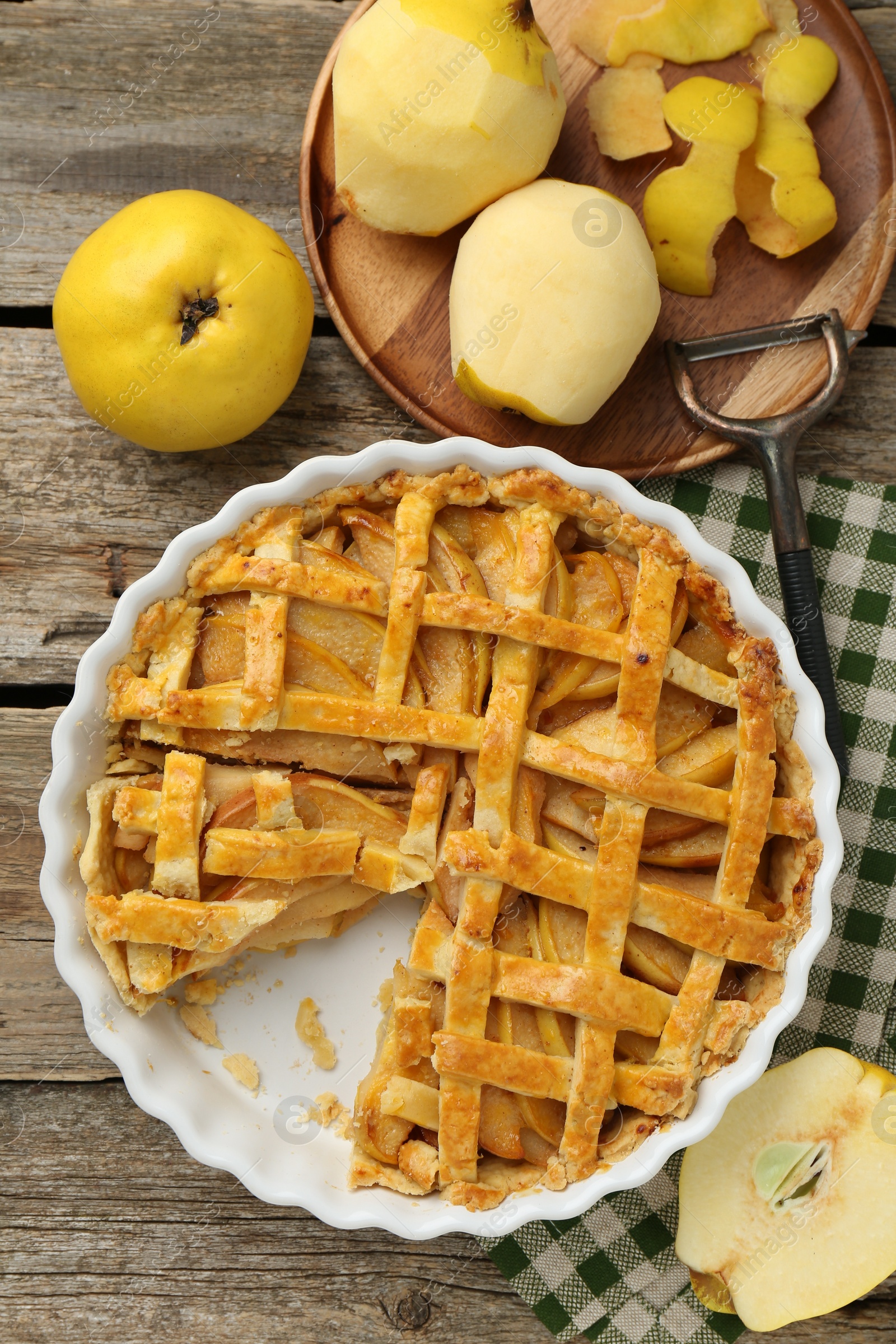 Photo of Tasty homemade quince pie, fresh fruits and peeler on wooden table, flat lay