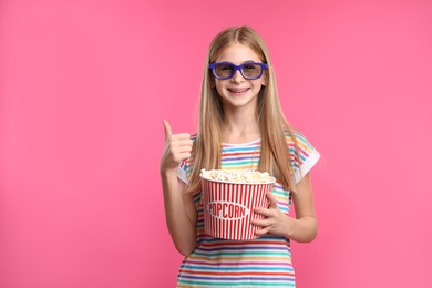 Teenage girl with 3D glasses and popcorn during cinema show on color background