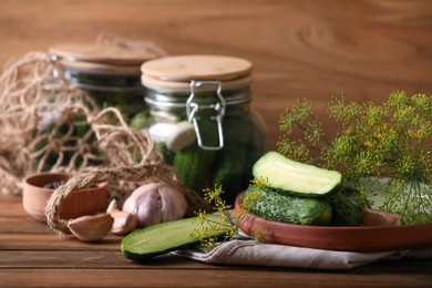 Photo of Fresh cucumbers and other ingredients prepared for canning on wooden table