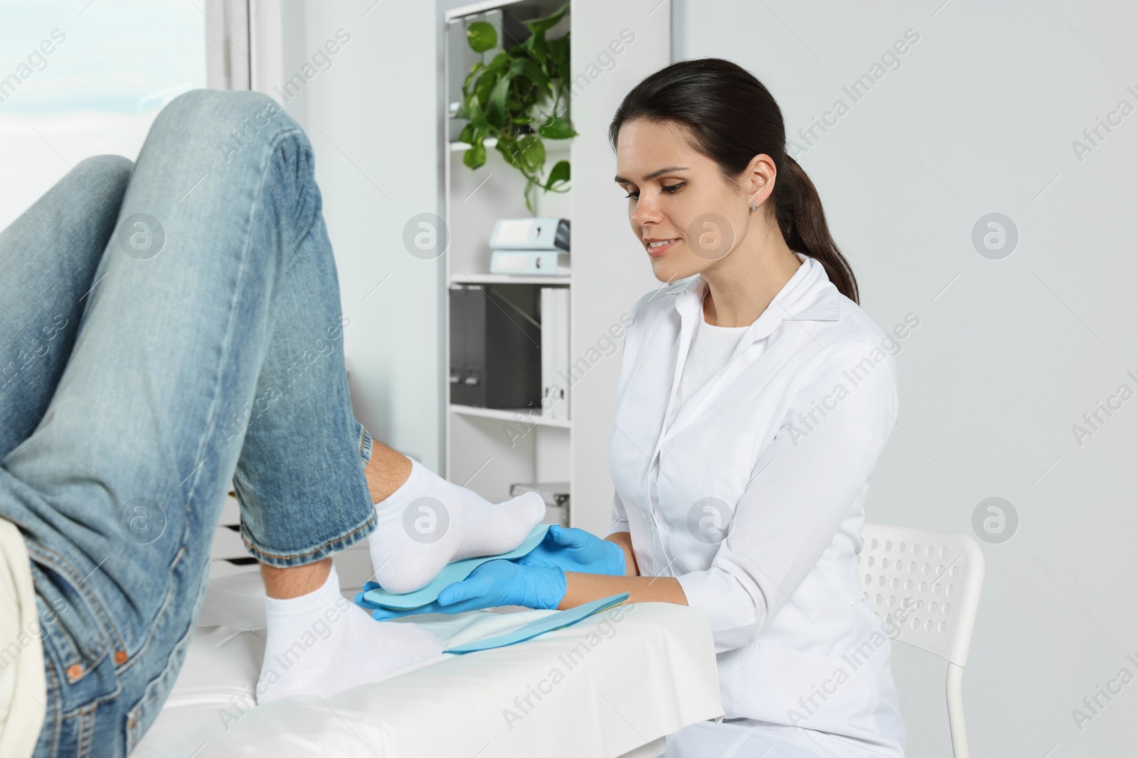 Photo of Beautiful female orthopedist fitting insole to patient's foot in hospital