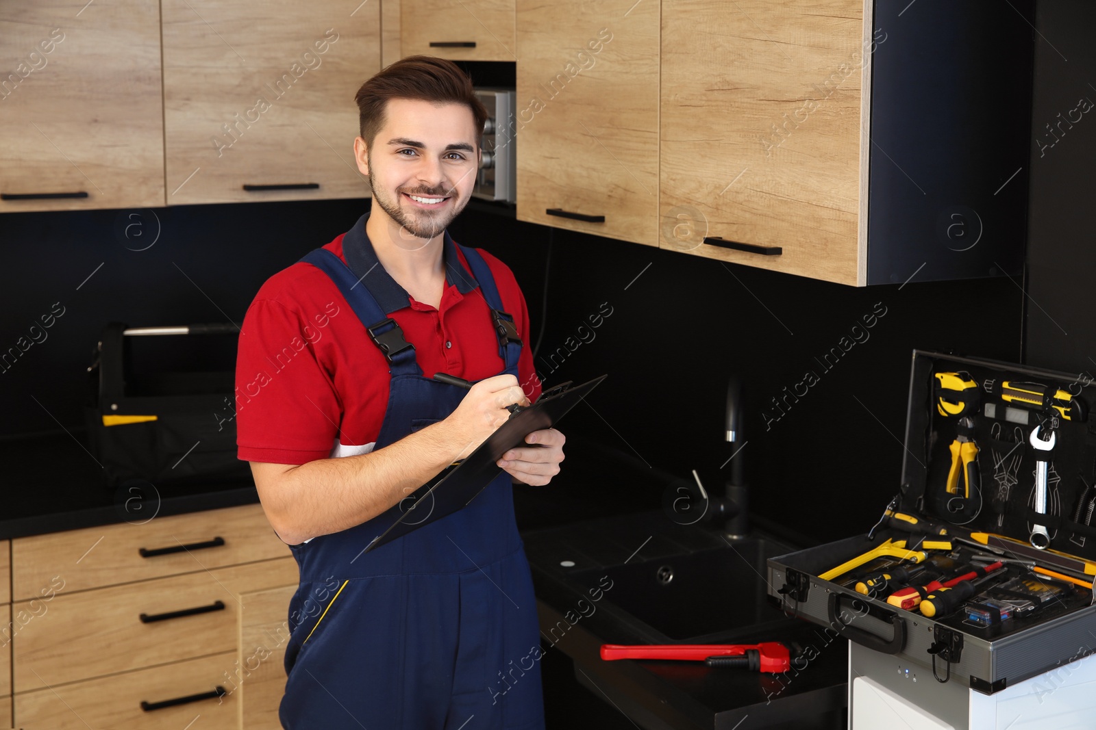 Photo of Male plumber with clipboard in kitchen. Repair service