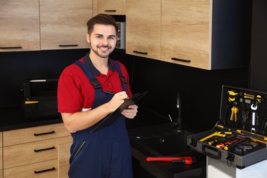 Photo of Male plumber with clipboard in kitchen. Repair service