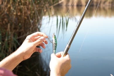 Photo of Man fishing alone at riverside on sunny day, closeup