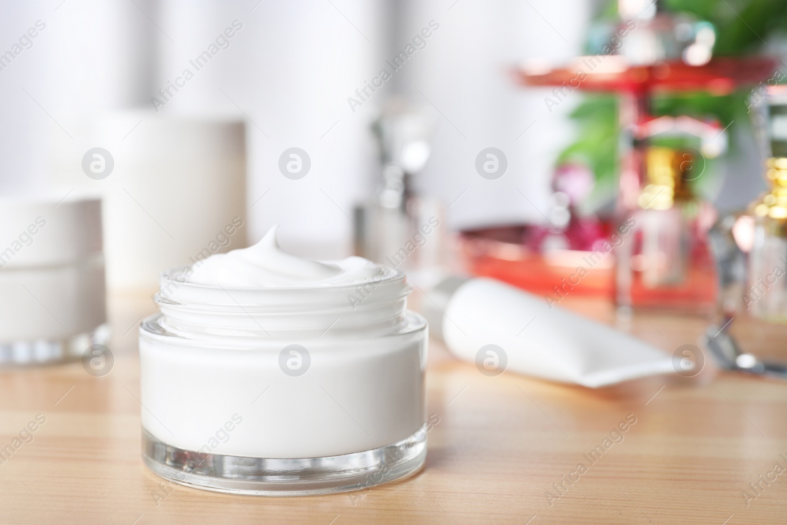 Photo of Open jar of cream on wooden dressing table. Space for text